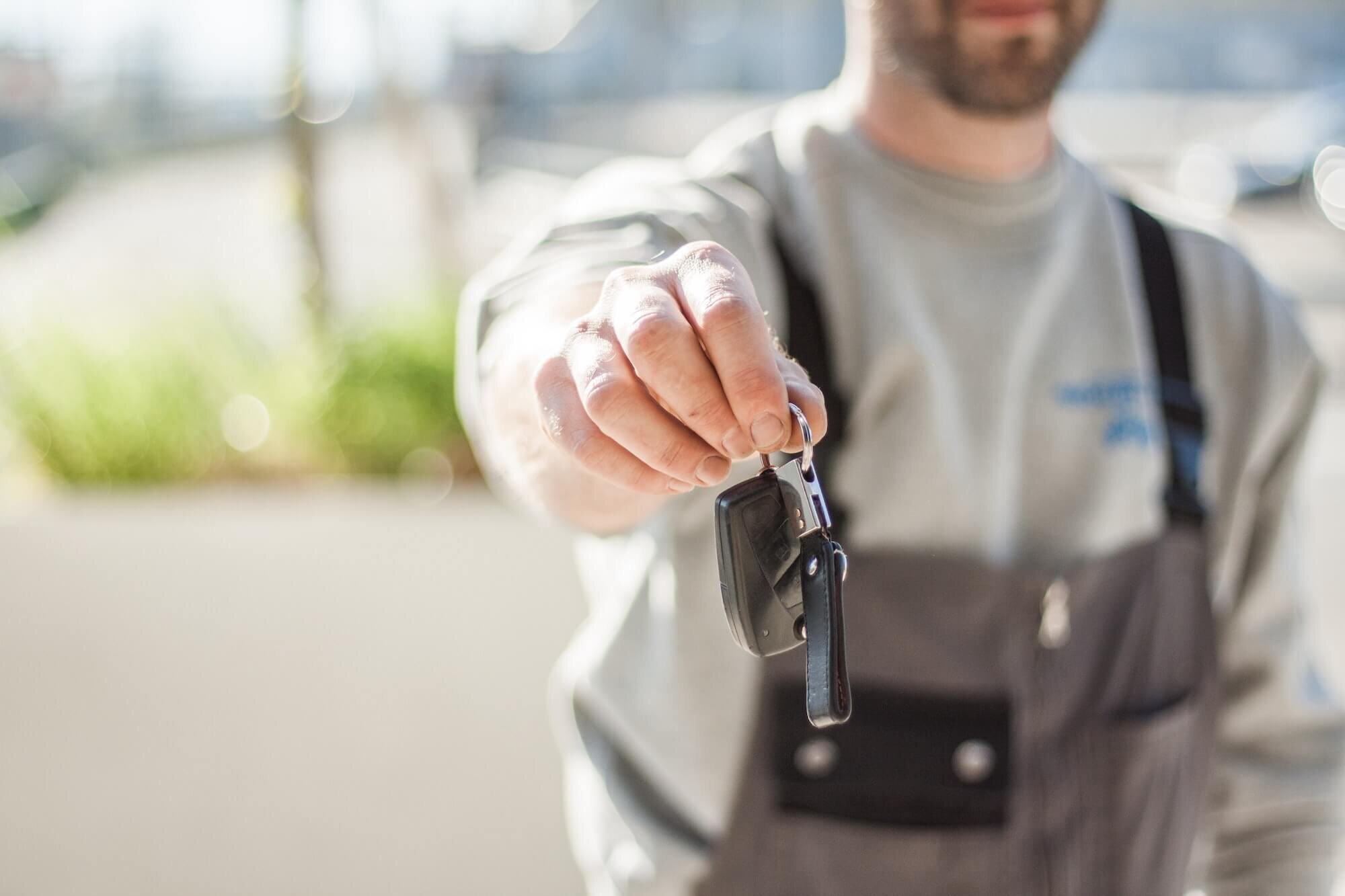 Mitarbeiter eines Autohauses übergibt einen Autoschlüssel
