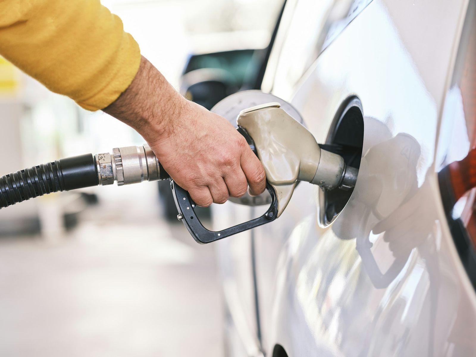 Fuel nozzle in the filler neck of a white car